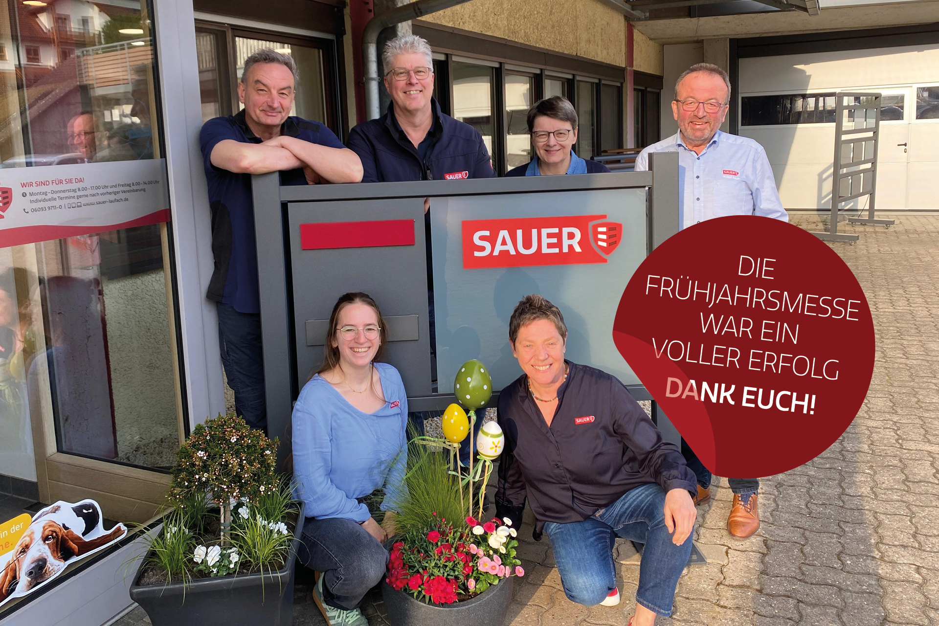 Die Geschäftsführung und Mitarbeitende der Firma Sauer als Gruppenbild an Firmenschild